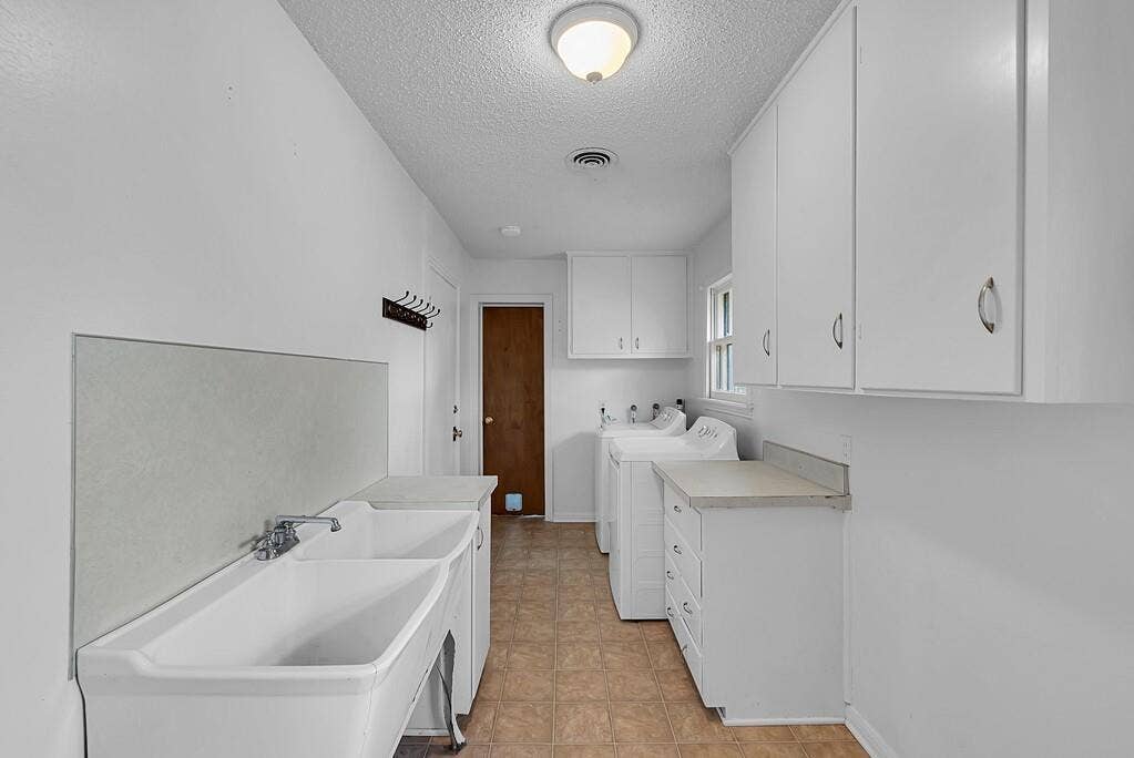 3917 Morrow Avenue, Waco, TX 76710 Laundry room with a textured ceiling, separate washer and dryer, cabinet space, and light flooring