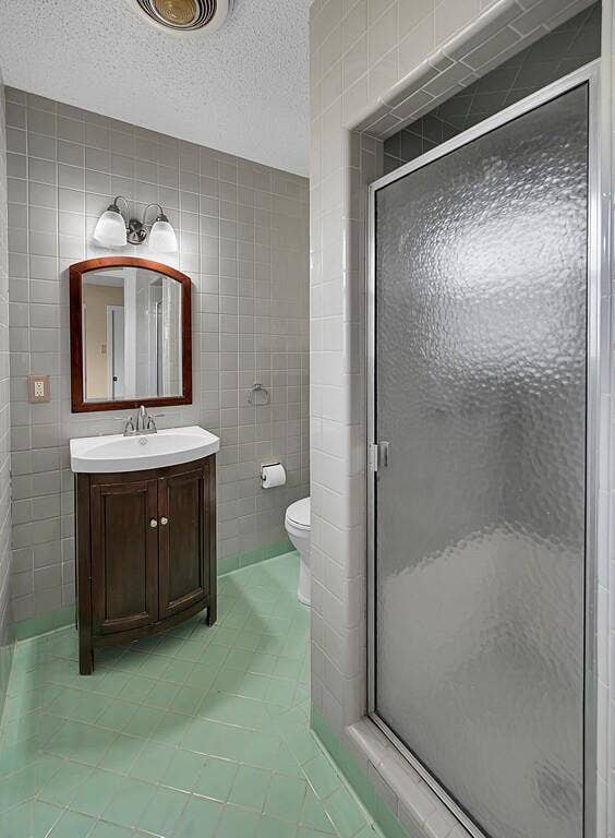 3917 Morrow Avenue, Waco, TX 76710 Full bath featuring tile walls, light tile patterned floors, vanity, a textured ceiling, and a stall shower
