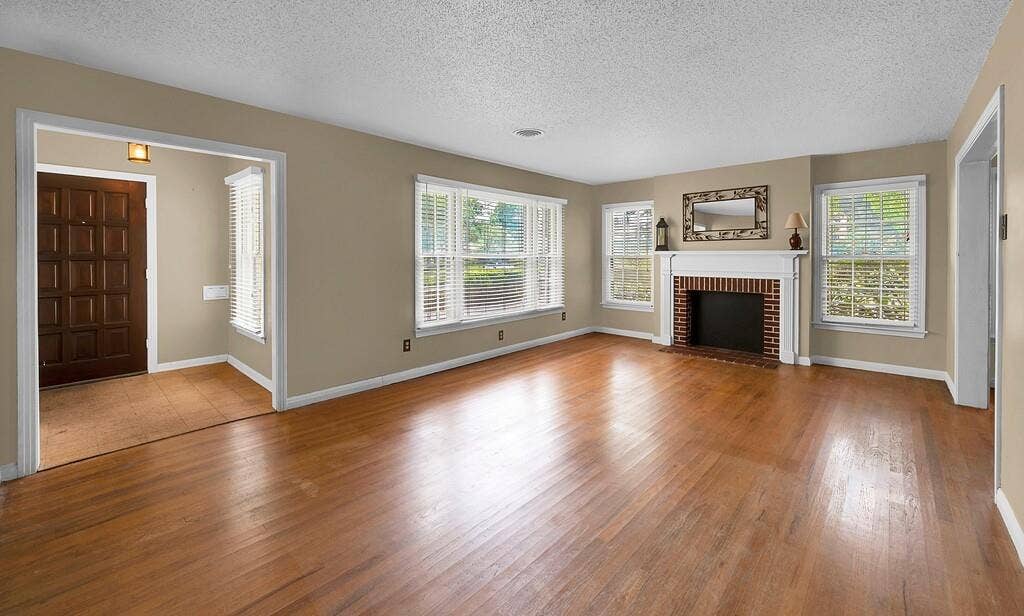 3917 Morrow Avenue, Waco, TX 76710 Unfurnished living room with hardwood / wood-style floors, a textured ceiling, and a fireplace