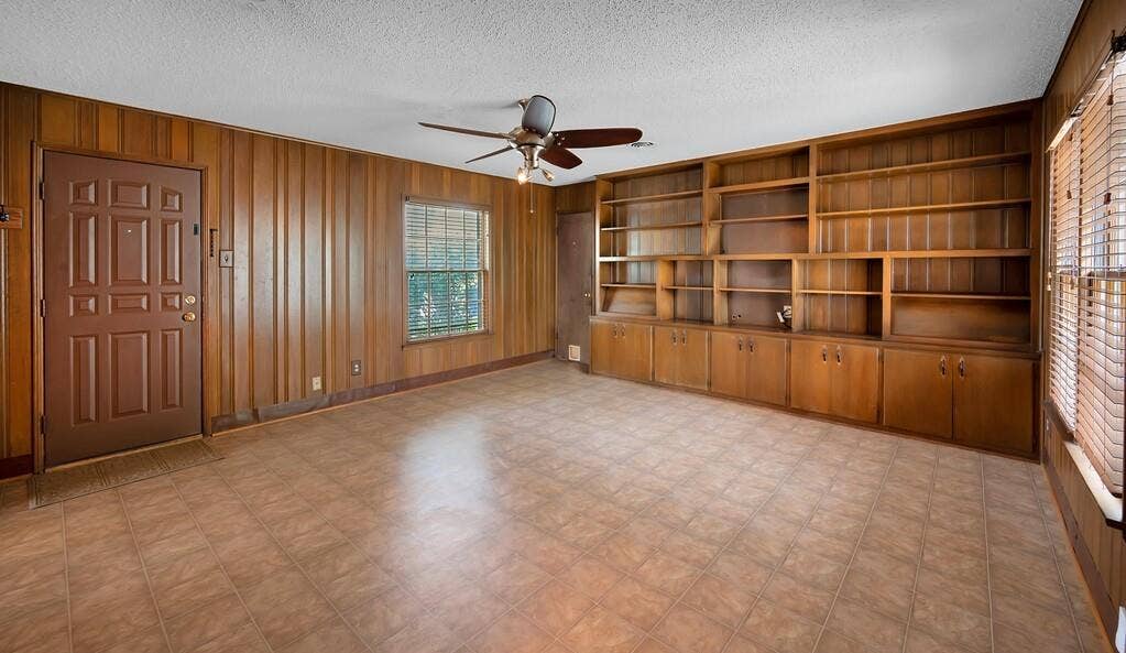 3917 Morrow Avenue, Waco, TX 76710 Unfurnished living room with ceiling fan, wood walls, light floors, a textured ceiling, and built in shelves
