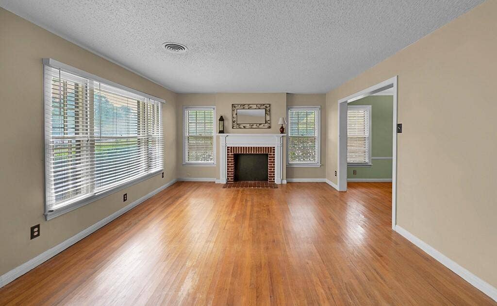3917 Morrow Avenue, Waco, TX 76710 Unfurnished living room with light wood-type flooring, a fireplace, and a textured ceiling