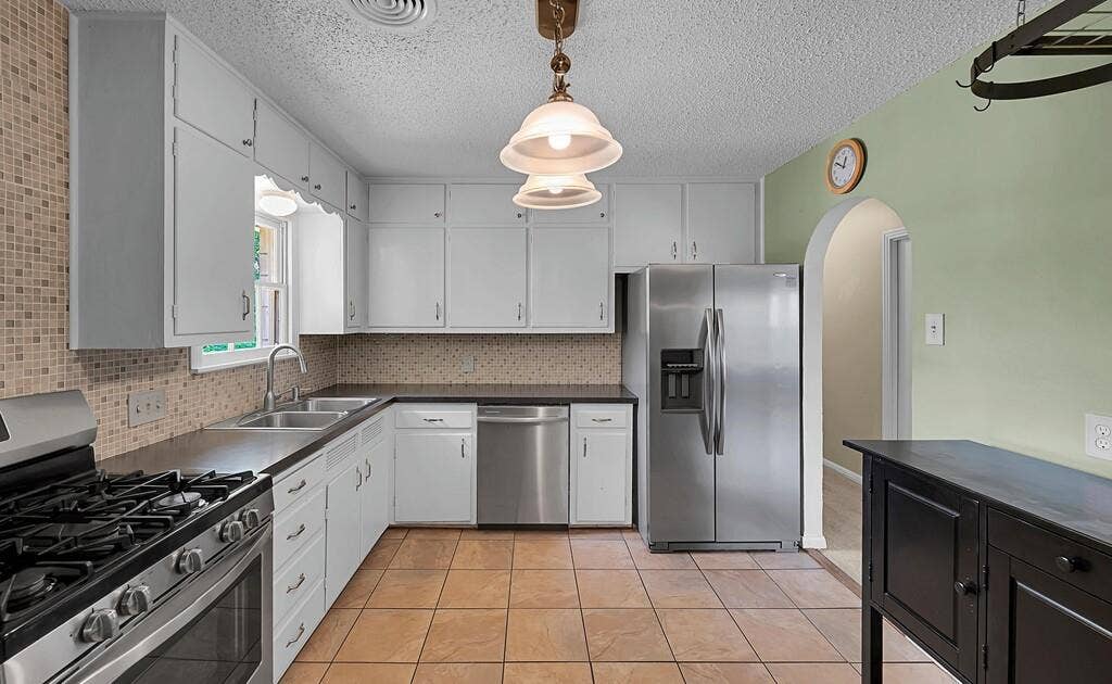 3917 Morrow Avenue, Waco, TX 76710 Kitchen featuring stainless steel appliances, dark countertops, arched walkways, a textured ceiling, and pendant lighting