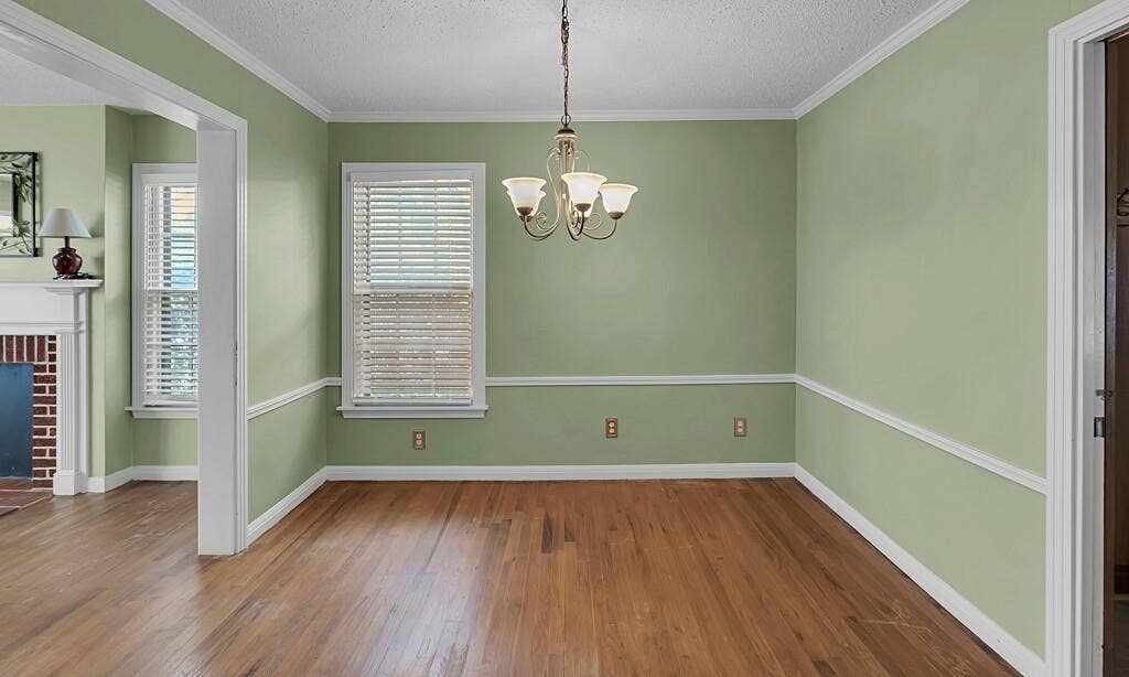 3917 Morrow Avenue, Waco, TX 76710 Unfurnished dining area featuring dark wood-style flooring, a fireplace, a textured ceiling, suspended lighting, and ornamental molding