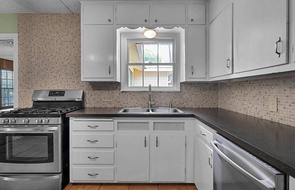 3917 Morrow Avenue, Waco, TX 76710 Kitchen with stainless steel appliances, white cabinets, dark countertops, light tile patterned floors, and decorative backsplash