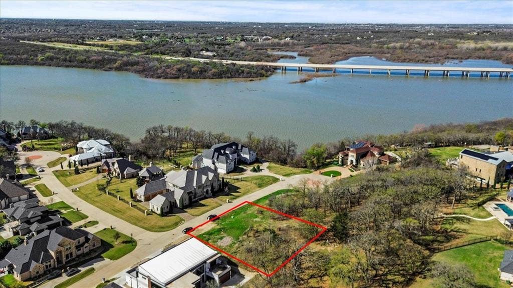 Aerial view of residential area with property boundaries highlighted and a large body of water