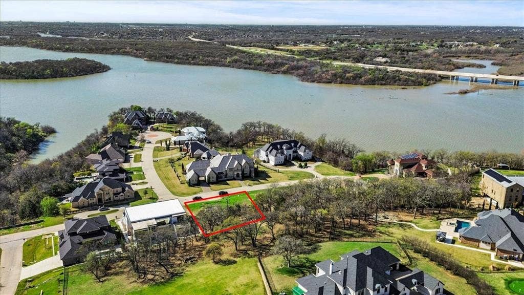 Aerial view of residential area featuring a nearby body of water and property parcel outlined