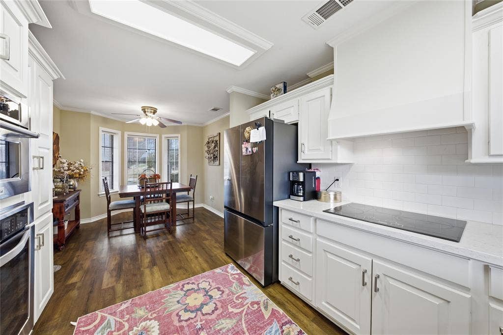 820 Torribrooke Lane, Athens, TX 75751 Kitchen with crown molding, white cabinetry, dark wood-style flooring, stainless steel appliances, and light stone counters