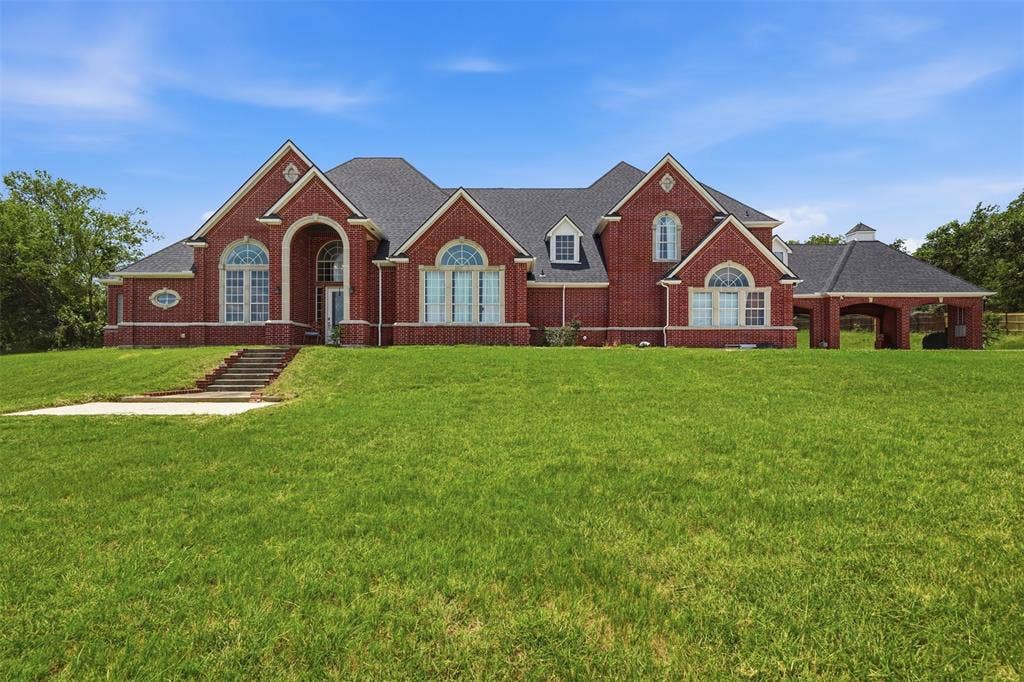 451 Land Of Goshen Drive, Springtown, TX 76082 Brick exterior residence featuring a prominent arched entry, multiple arched windows, and a portico with an attached cupola