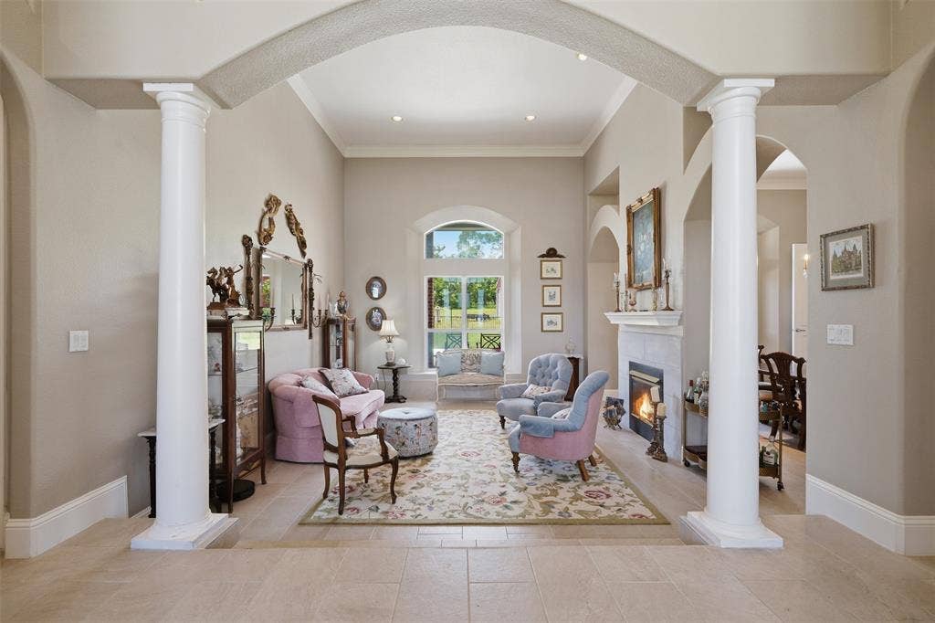 451 Land Of Goshen Drive, Springtown, TX 76082 Spacious living area featuring architectural columns, elegant arched doorways, a built-in fireplace with a mantel, high vaulted ceilings, and large arched windows providing abundant natural light