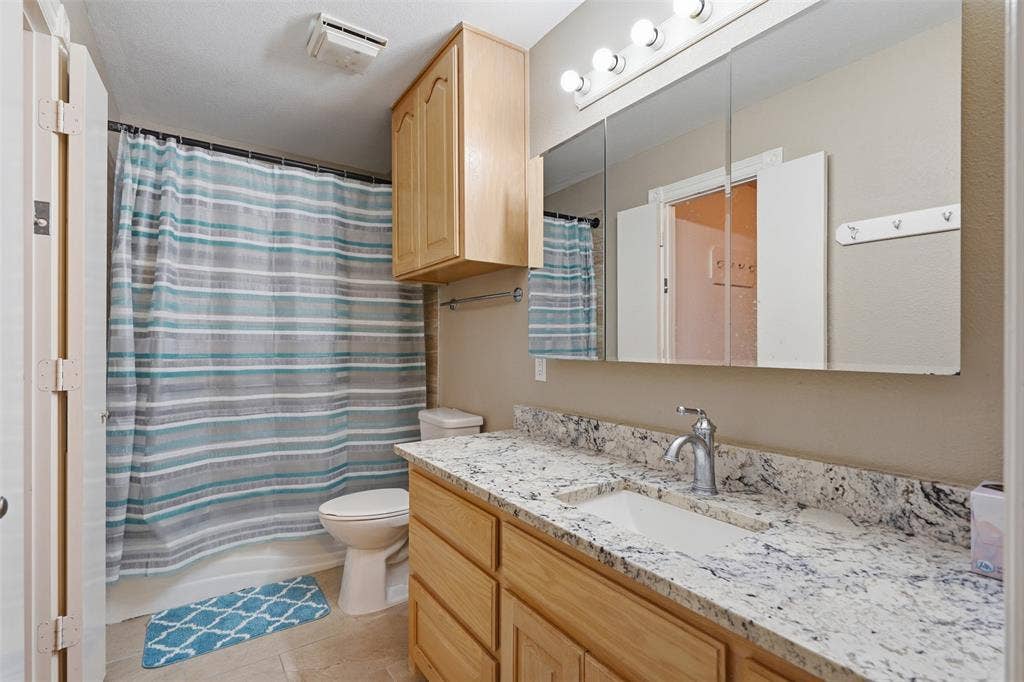 451 Land Of Goshen Drive, Springtown, TX 76082 Bathroom featuring a spacious vanity with a light-colored, patterned countertop, an integrated rectangular sink, and a chrome faucet