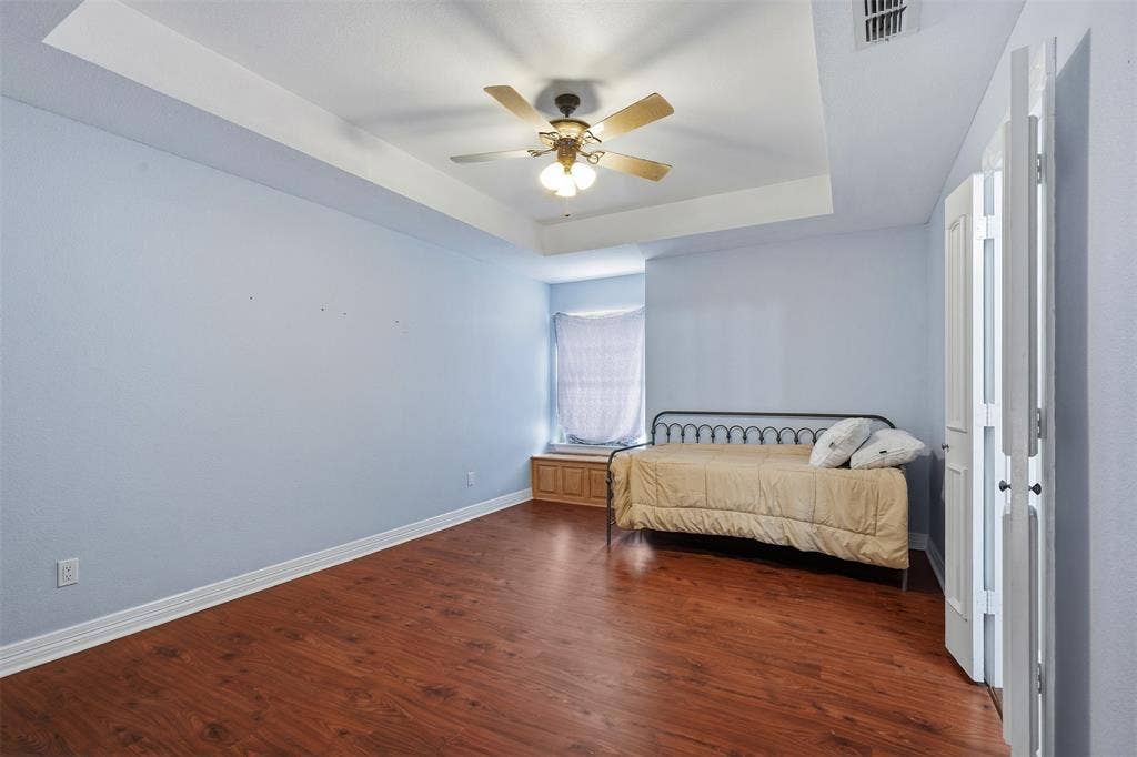 451 Land Of Goshen Drive, Springtown, TX 76082 Spacious interior featuring wood-finish flooring, a tray ceiling, and a ceiling fan with integrated lighting