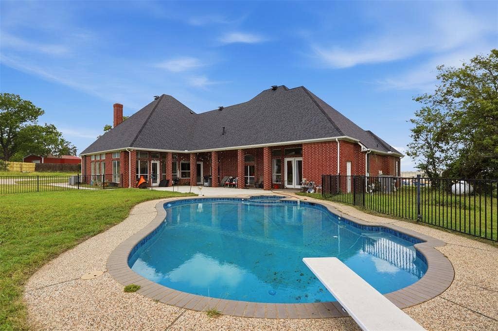 451 Land Of Goshen Drive, Springtown, TX 76082 Expansive backyard featuring a large in-ground swimming pool with a diving board, brick exterior, covered patio, and perimeter fencing
