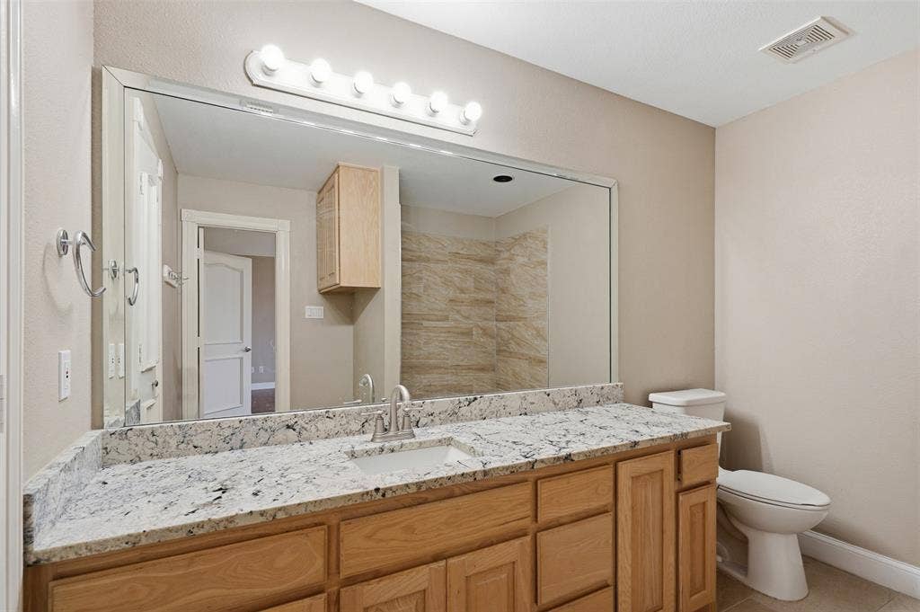 451 Land Of Goshen Drive, Springtown, TX 76082 Bathroom vanity featuring a light-toned stone countertop, dual sinks, and light wood cabinetry