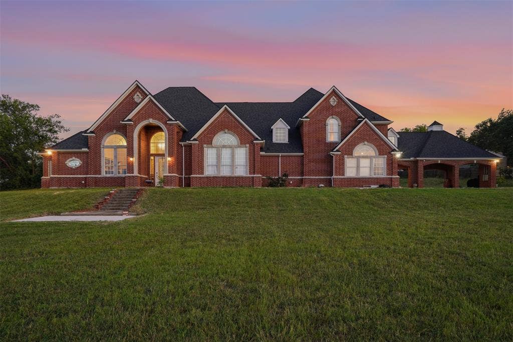 451 Land Of Goshen Drive, Springtown, TX 76082 Brick exterior residence featuring a prominent arched entry, multiple gabled rooflines, and a covered porte-cochère