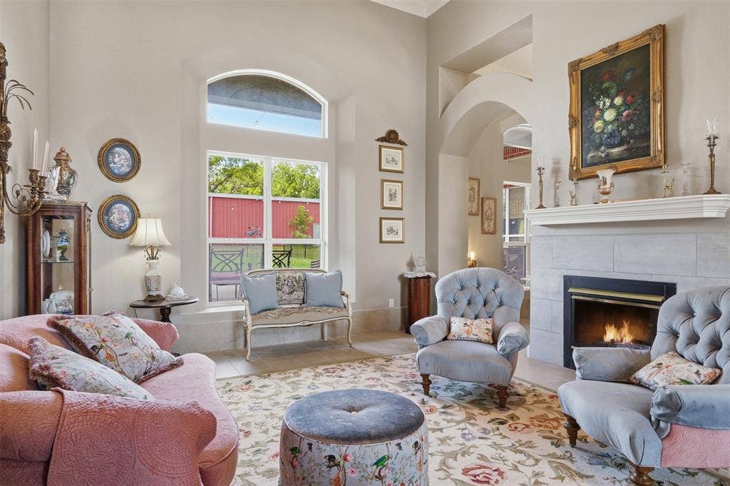 451 Land Of Goshen Drive, Springtown, TX 76082 Spacious living area featuring a fireplace with a light-toned tile surround and mantle, arched doorways, a large window with an arched transom, and high ceilings