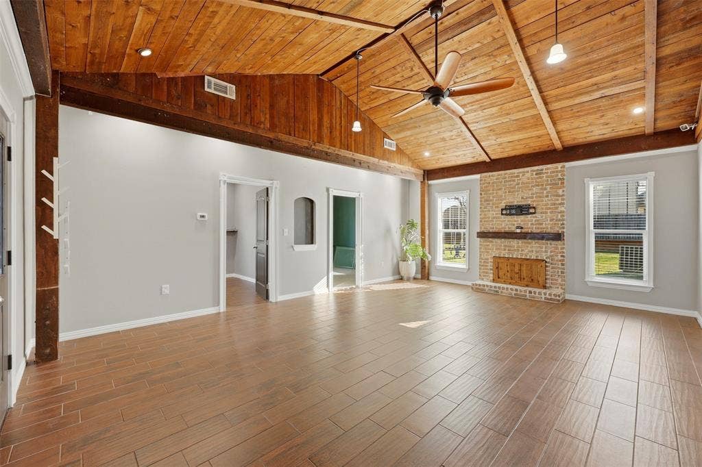 113 Mulkey Road, Waxahachie, TX 75167 Unfurnished living room with ceiling fan, a brick fireplace, wood tiled floors, and a vaulted wooden ceiling