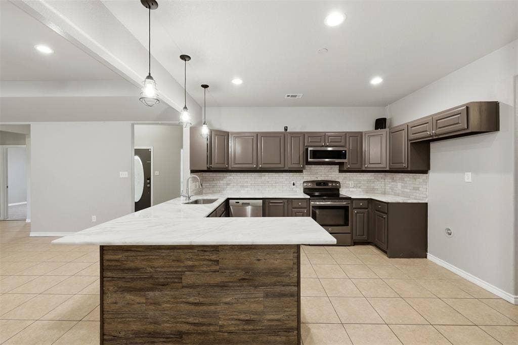 113 Mulkey Road, Waxahachie, TX 75167 Kitchen featuring stainless steel appliances, a peninsula, light tile patterned floors, hanging light fixtures, and dark wood finish cabinetry