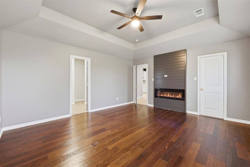 113 Mulkey Road, Waxahachie, TX 75167 Bedroom with a tray ceiling, a fireplace, dark wood-style flooring, and a ceiling fan