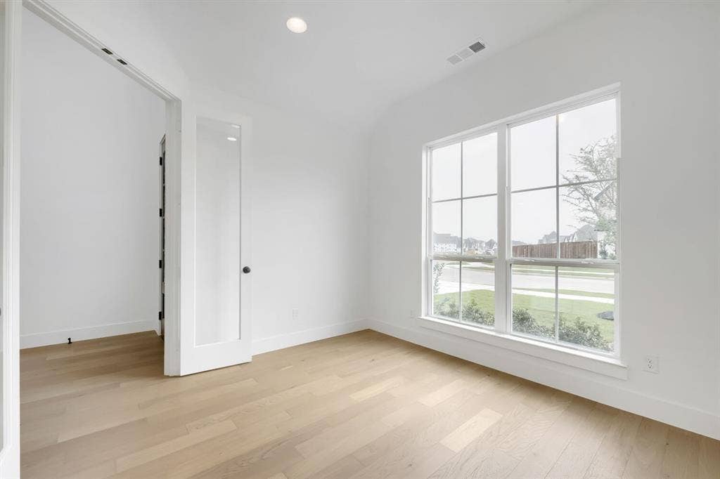 733 Red Cedar Road, Haslet, TX 76052 Bright interior space featuring a large grid-pane window, wood-finish flooring, recessed lighting, and a glass-paneled door