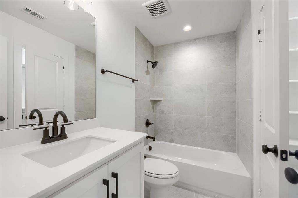 733 Red Cedar Road, Haslet, TX 76052 Bathroom featuring a white vanity with an integrated sink, dark bronze fixtures, light gray subway tile shower surround with a built-in niche, and recessed lighting