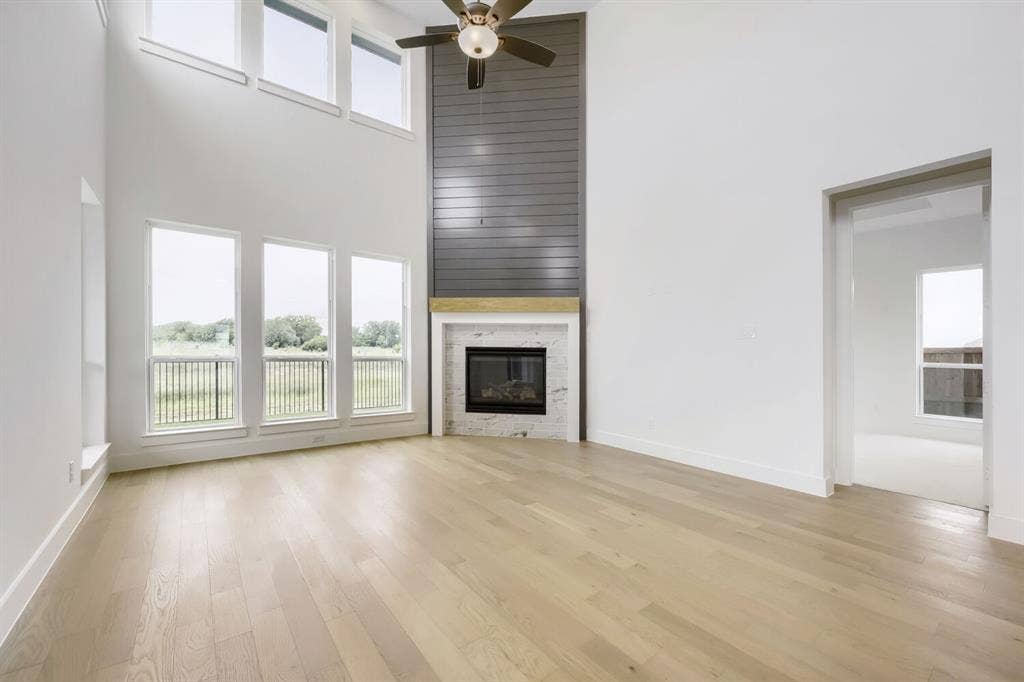 733 Red Cedar Road, Haslet, TX 76052 Open concept living area featuring a two-story ceiling, light wood-finish flooring, and a contemporary fireplace with a marble surround and wood mantel
