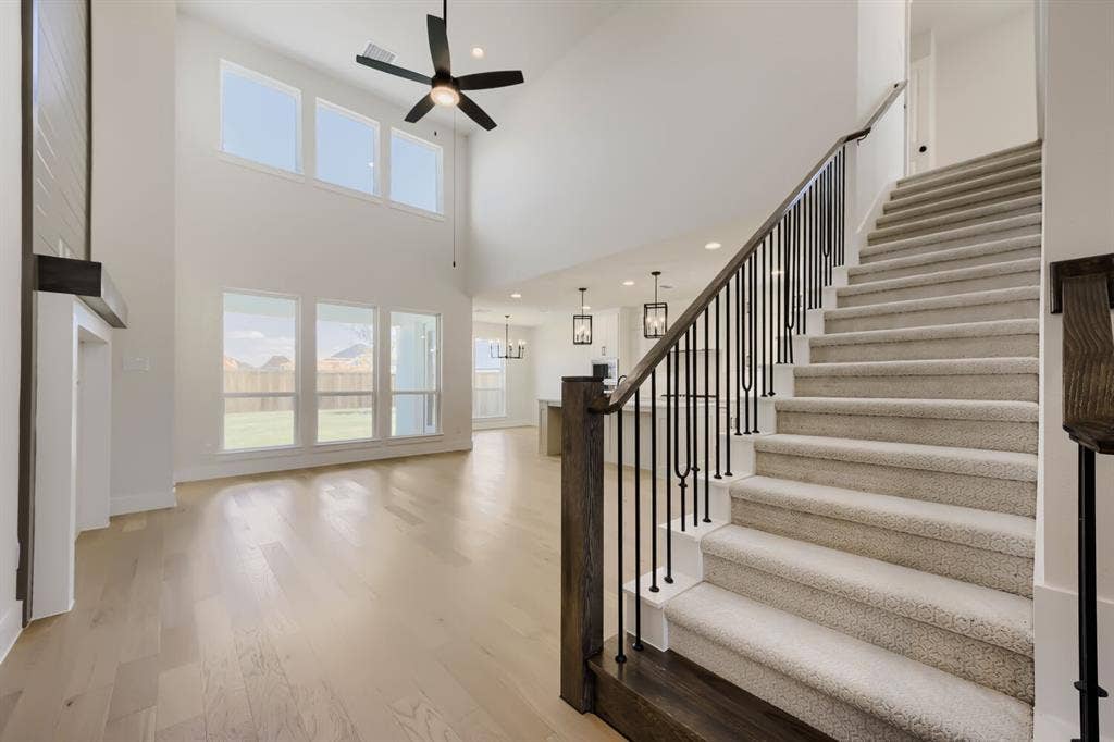 1241 Greenbriar Avenue, Haslet, TX 76052 Two-story foyer featuring a carpeted staircase with dark wood newel posts and black iron balusters, light wood-finish flooring, and a two-story window wall