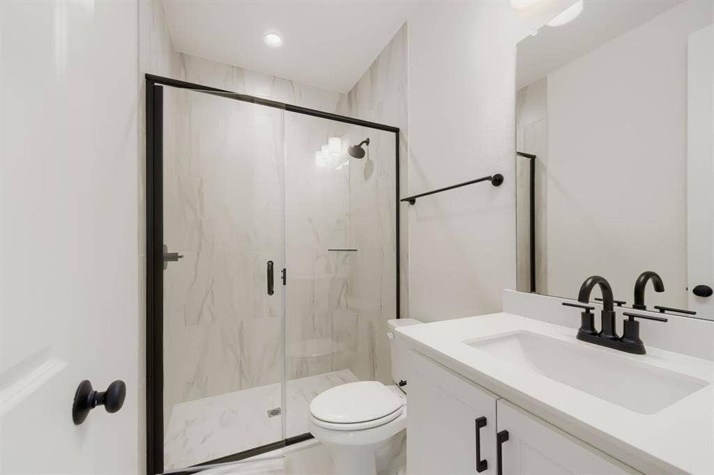 1241 Greenbriar Avenue, Haslet, TX 76052 Contemporary bathroom featuring a frameless glass shower enclosure with matte black hardware, white vanity with integrated sink, and coordinating matte black faucet