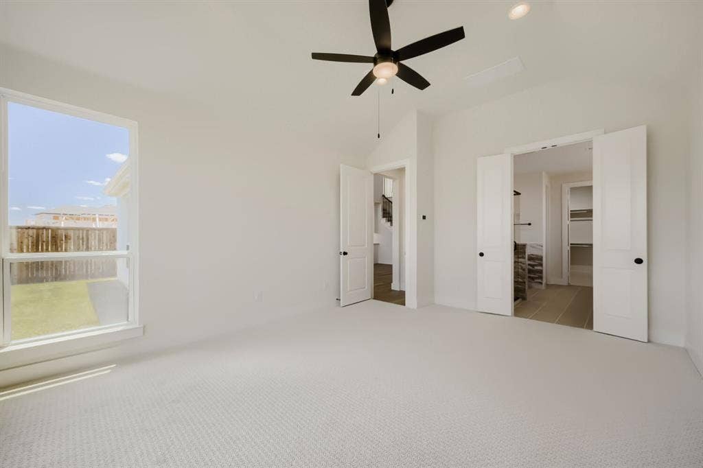 1241 Greenbriar Avenue, Haslet, TX 76052 Carpeted room featuring a ceiling fan with light, a large window, and double doors opening to a separate space with tiled flooring