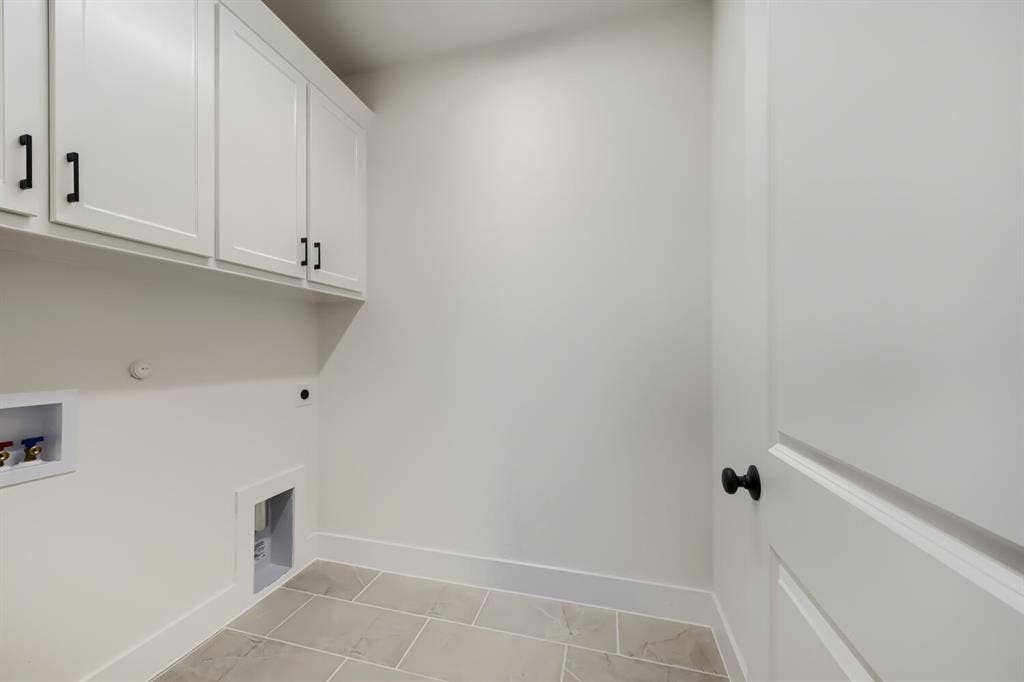 1241 Greenbriar Avenue, Haslet, TX 76052 Utility room featuring upper cabinetry with black hardware, white walls, and light-toned rectangular floor tiles