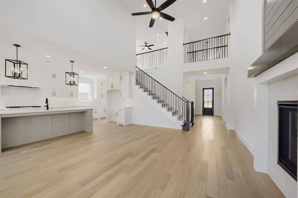 1241 Greenbriar Avenue, Haslet, TX 76052 Open-concept living area featuring light wood-finish flooring, a two-story ceiling, and a prominent fireplace with a shiplap accent