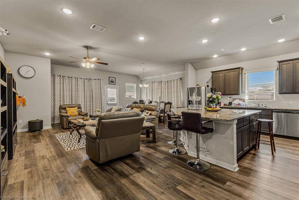5408 Wedge Wood Drive, Haltom City, TX 76137 Living room featuring dark wood finished floors, ceiling fan, plenty of natural light, and suspended lighting