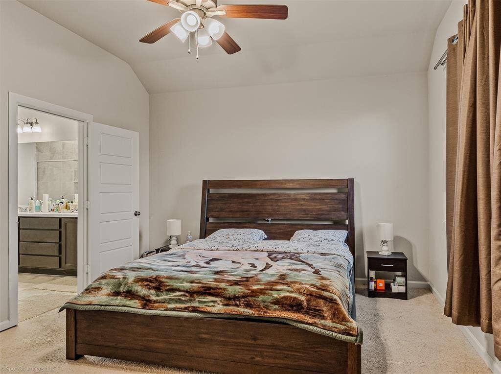 5408 Wedge Wood Drive, Haltom City, TX 76137 Bedroom featuring lofted ceiling, a ceiling fan, ensuite bathroom, and light carpet