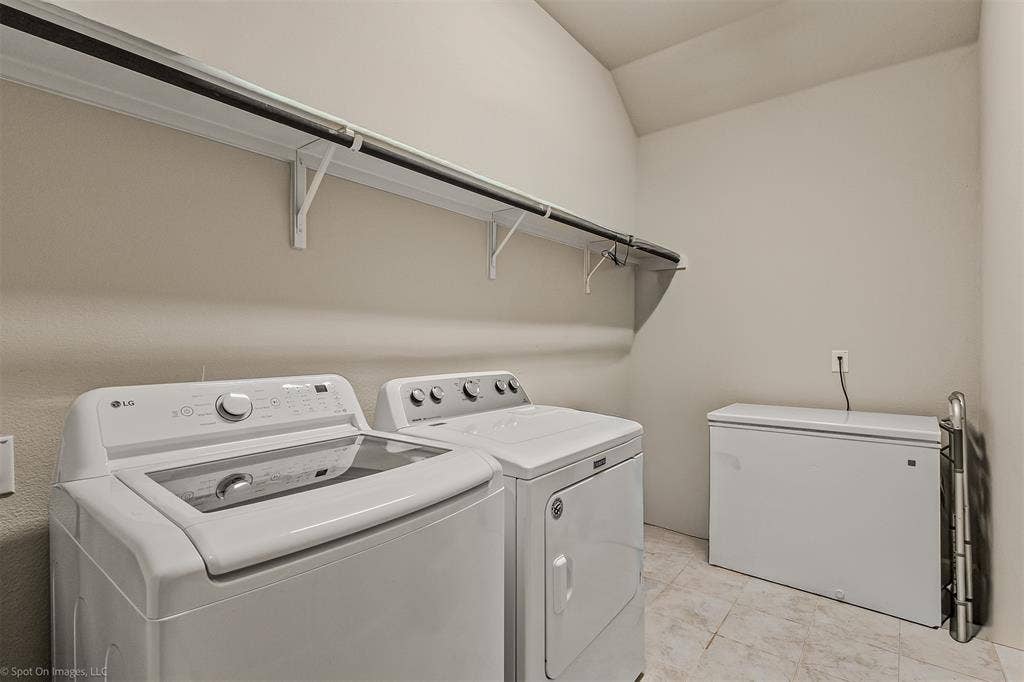 5408 Wedge Wood Drive, Haltom City, TX 76137 Laundry area featuring vaulted ceiling and washing machine and dryer