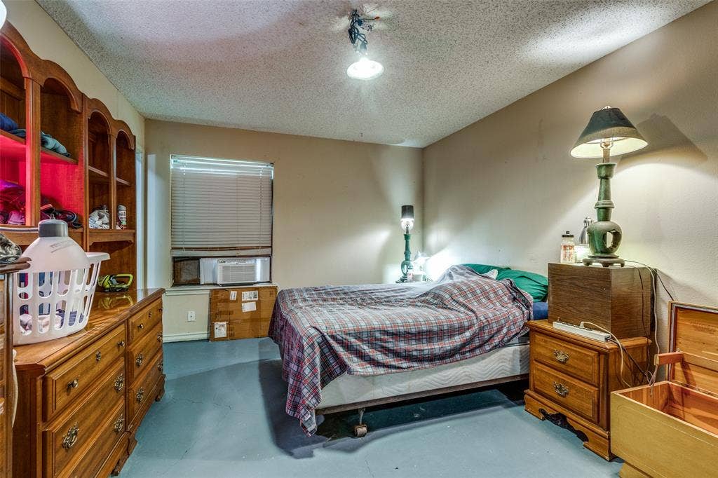 Bedroom featuring a textured ceiling, cooling unit, and concrete floors