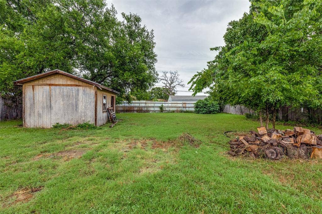 Fenced backyard featuring an outbuilding