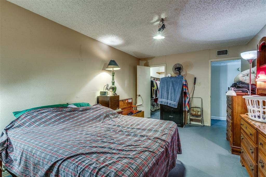 Bedroom featuring finished concrete floors, a textured ceiling, a walk in closet, and rail lighting