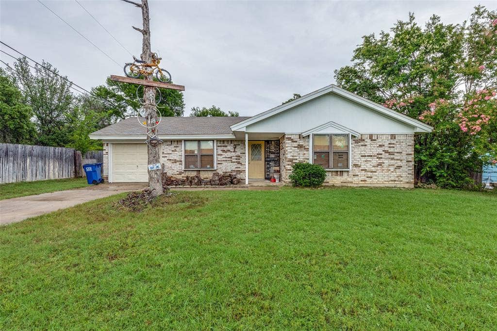 Single story home with driveway, a garage, and brick siding