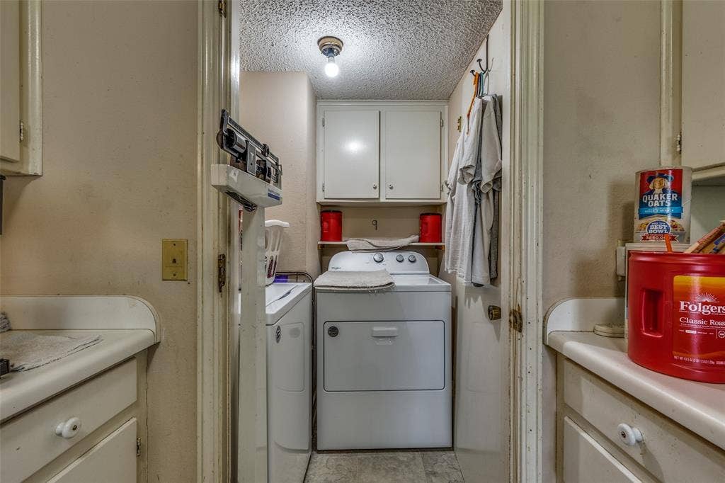 Laundry area with separate washer and dryer, cabinet space, and a textured ceiling