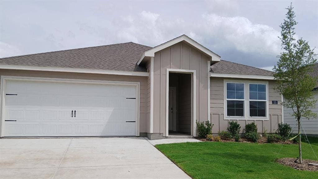315 Whispering Pine Drive, Royse City, TX 75189 Contemporary single-story residence featuring a two-car garage, beige siding with vertical accents, and a covered entry