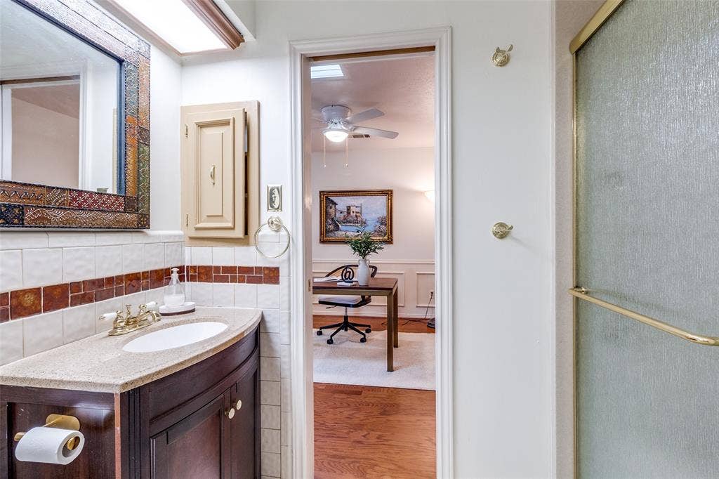 14810 Knollview Drive, Dallas, TX 75248 Bathroom featuring vanity, wood finished floors, wainscoting, a ceiling fan, and a shower with door