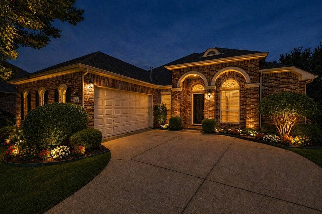 351 Southern Hills Drive, Fairview, TX 75069 Brick exterior with arched windows, an attached garage, and a concrete driveway - Virtually Staged