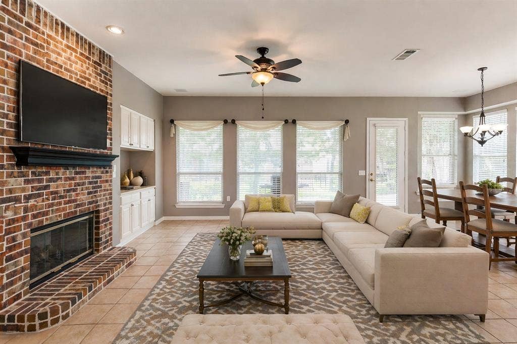 351 Southern Hills Drive, Fairview, TX 75069 Spacious living area featuring a brick fireplace, built-in cabinetry, tile flooring, a ceiling fan, and ample natural light through multiple windows - Virtually Staged