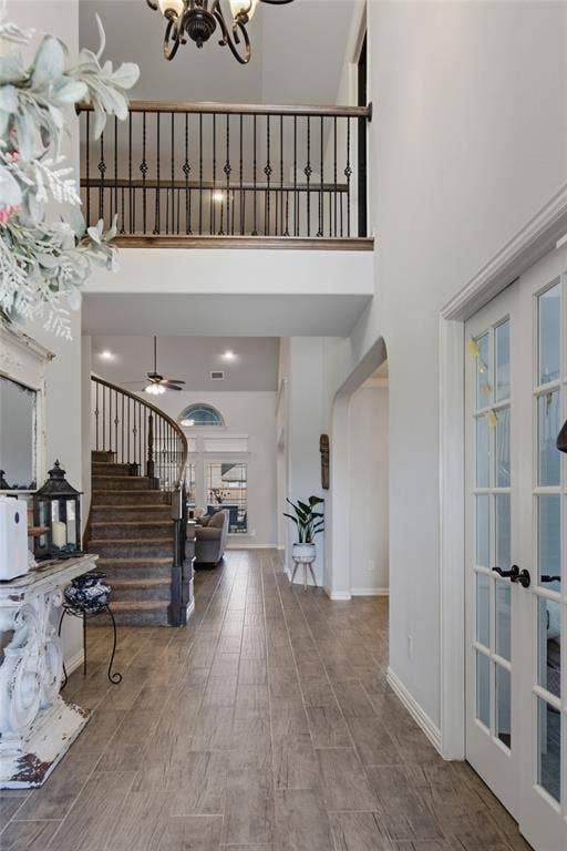 Two-story foyer featuring wood-finish tile flooring, a curved staircase with wrought iron balusters, a second-story overlook, and French doors to the flex space