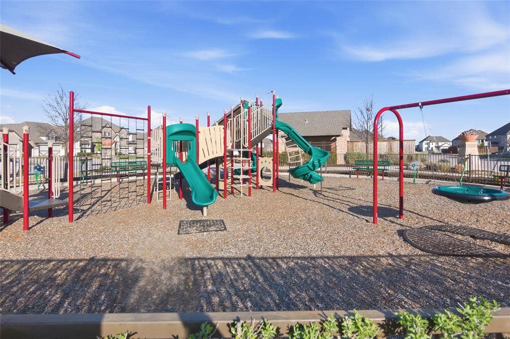Community playground featuring multiple slides, climbing structures, swings, and a protective ground covering