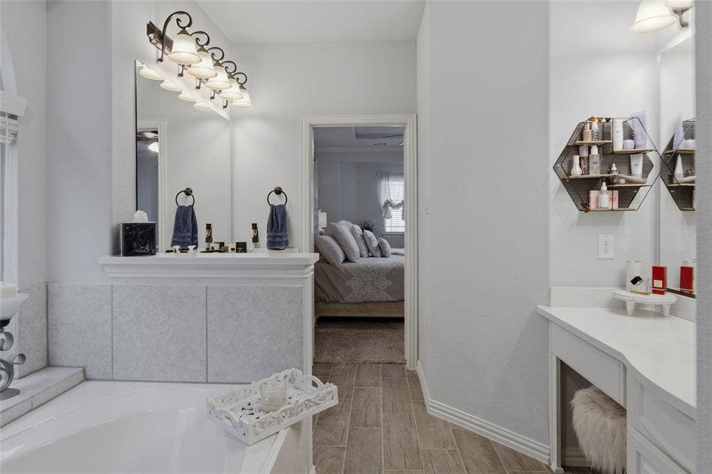 Master bathroom featuring a built-in vanity with a countertop, a bathtub, and wood-finish flooring. Speakers throughout to jam while getting ready for the day.