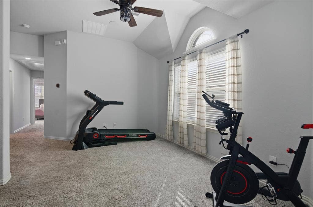 Upper-level bonus space featuring vaulted ceilings, a ceiling fan, and multiple windows with an arched transom