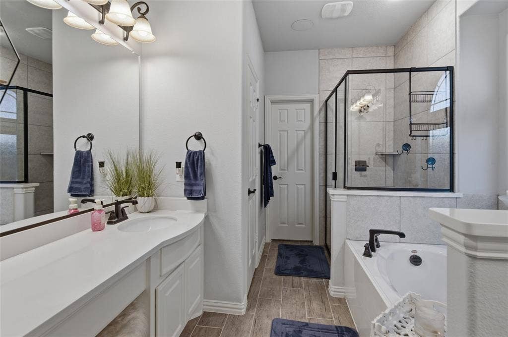 Contemporary bathroom featuring a spacious vanity with an undermount sink, a large mirror, and wood-finish flooring