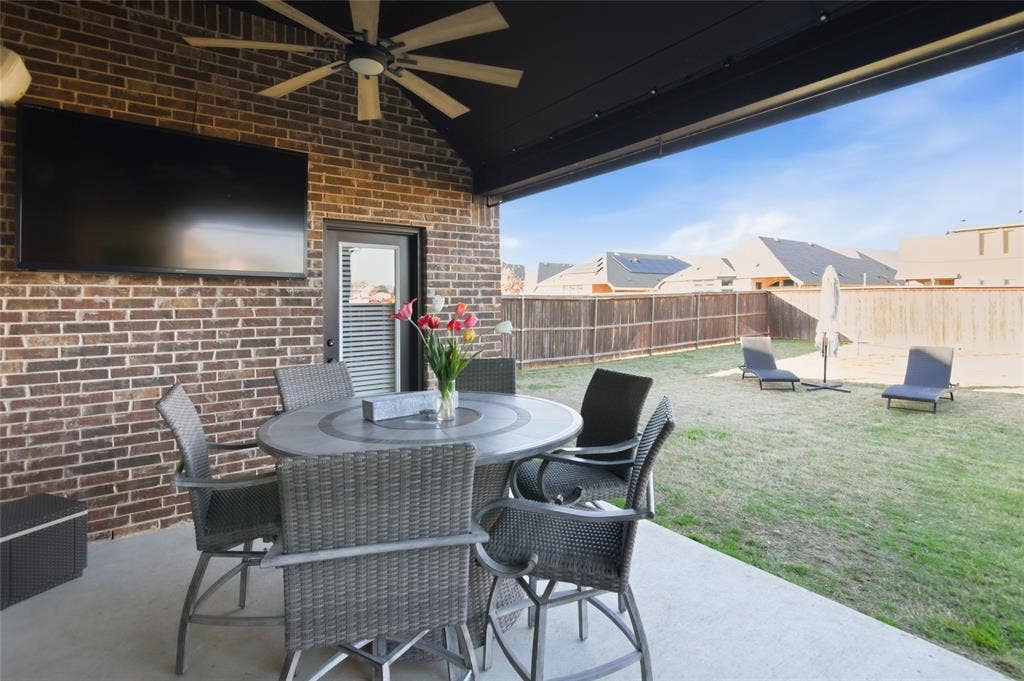 Covered patio with a high vaulted ceiling, exposed brick wall, and concrete flooring