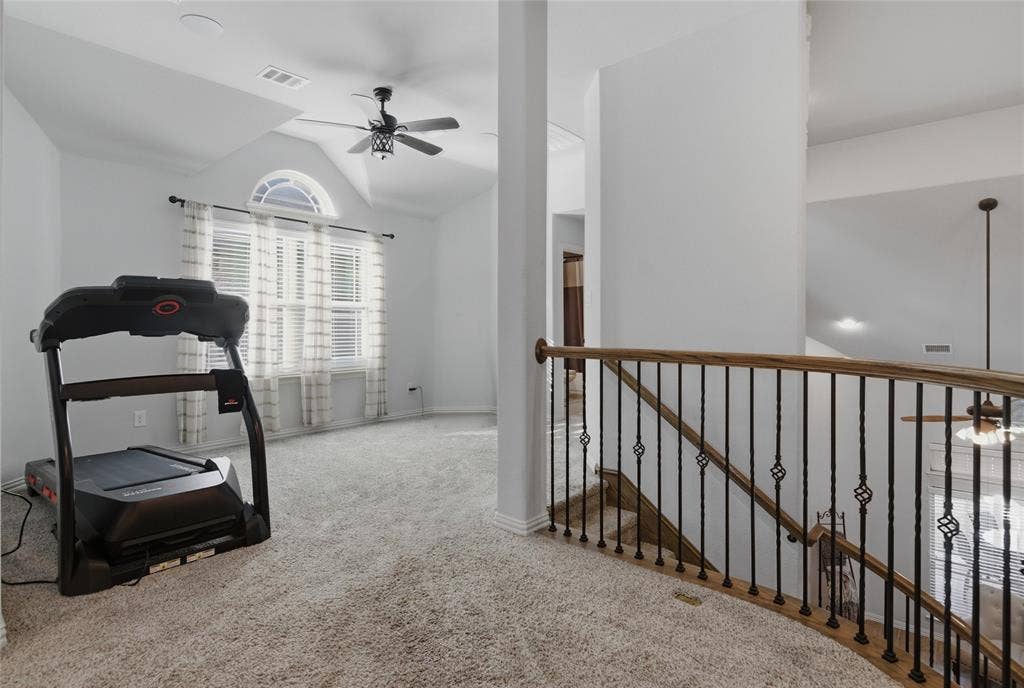 Carpeted upper-level landing featuring a wood-finish handrail with wrought iron balusters and a half-arch window