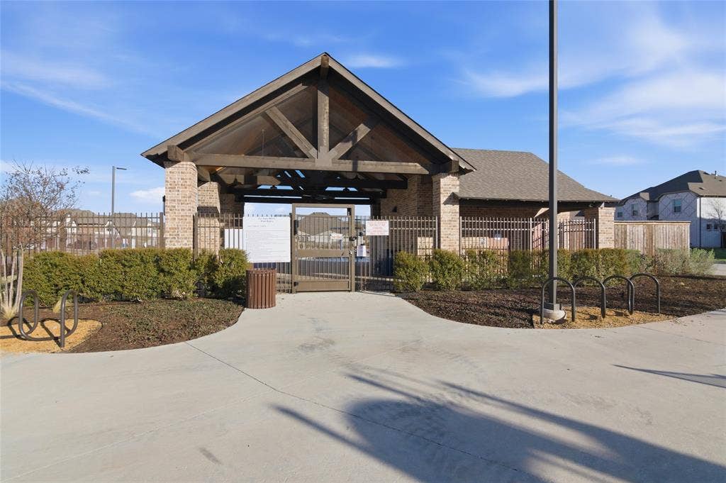 Community amenity center featuring a brick and timber-frame pavilion, iron fencing, and manicured landscaping